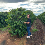 Elizabeth Martin standing in front of her coffee plants on her farm.
