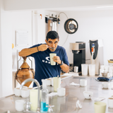 Man in a kitchen cupping with various coffee-making equipment around him.